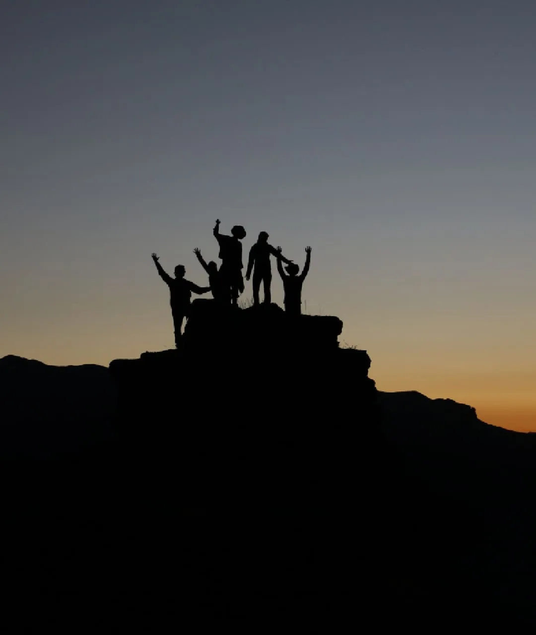 En gruppe mennesker på en fjelltopp i solnedgang